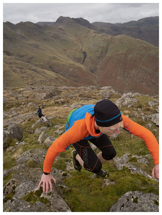 Läufer in orangen OMM Core+ Hoodie in den Bergen