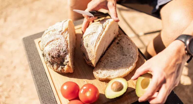 Ein Schneidebrett mit geschnittenem Brot, Avocado und Tomaten