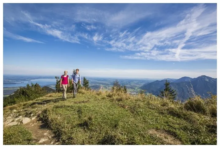 Eine Wanderin mit einem Wanderer in den Bergen unterwegs.