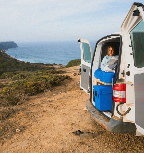 Eine Frau in einem Wohnwagen an der Küste mit einer blauen Kühlbox von Qool